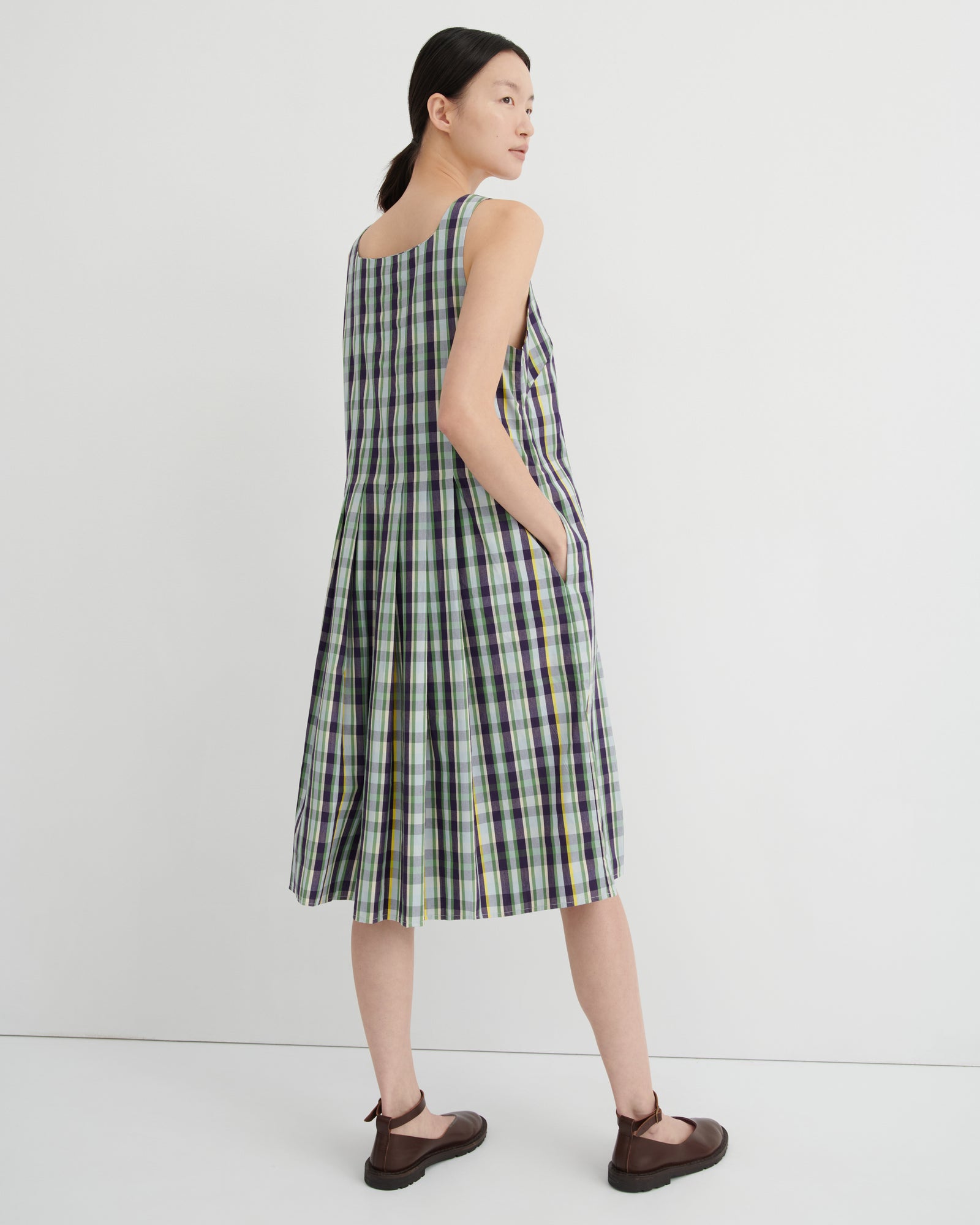Woman wearing a green and white checkered dress against a white background
