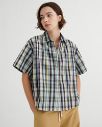 Person wearing a plaid shirt with a plain background