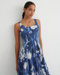 Woman wearing a blue and white tie-dye dress against a plain background