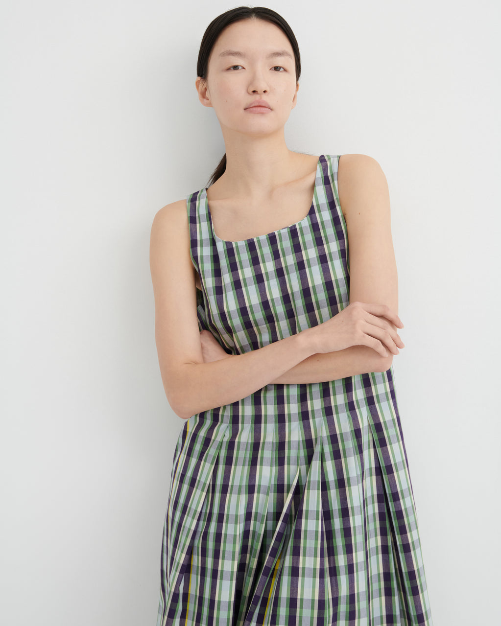 Woman wearing a green and purple checkered dress against a white background