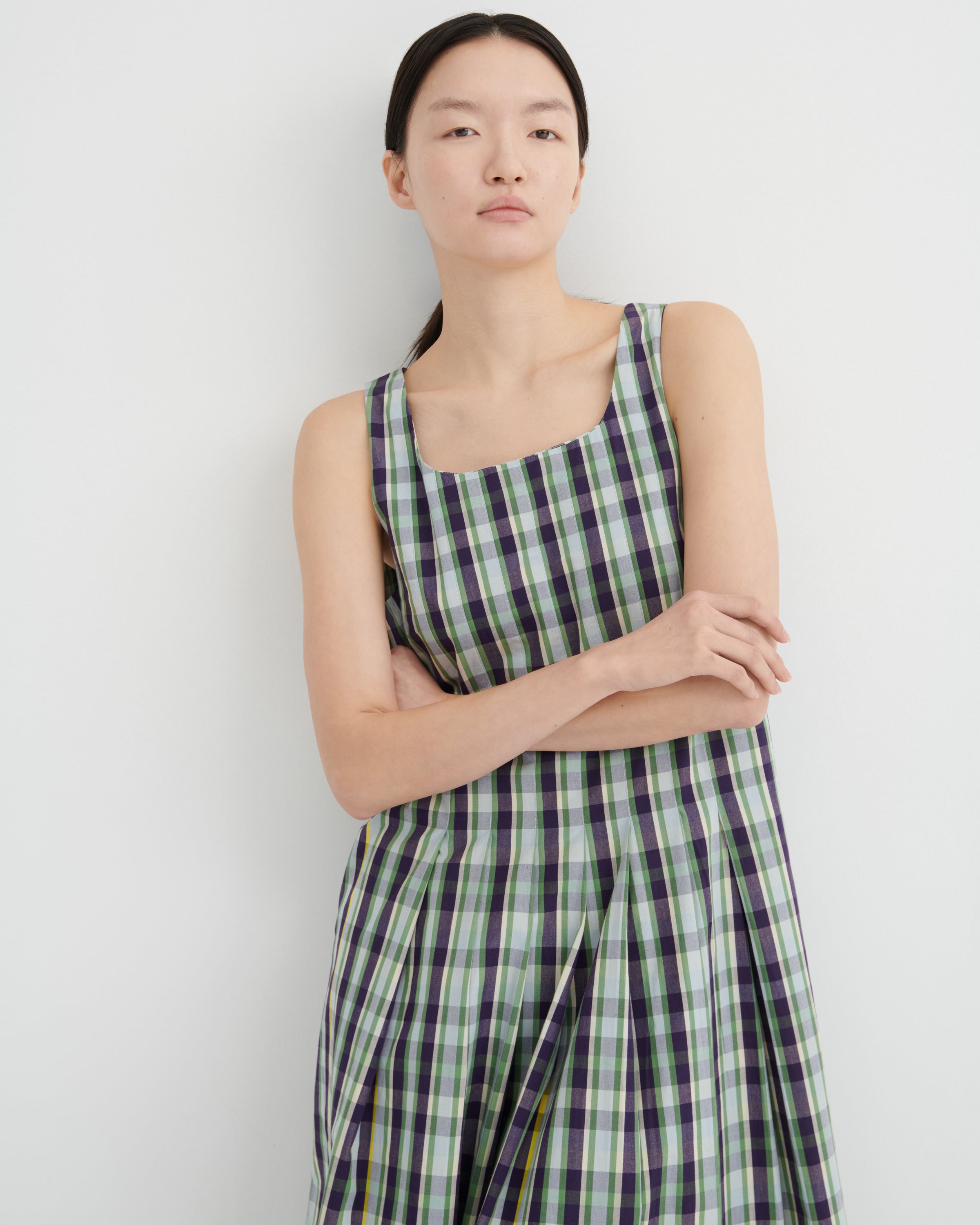 Woman wearing a green and purple checkered dress against a white background
