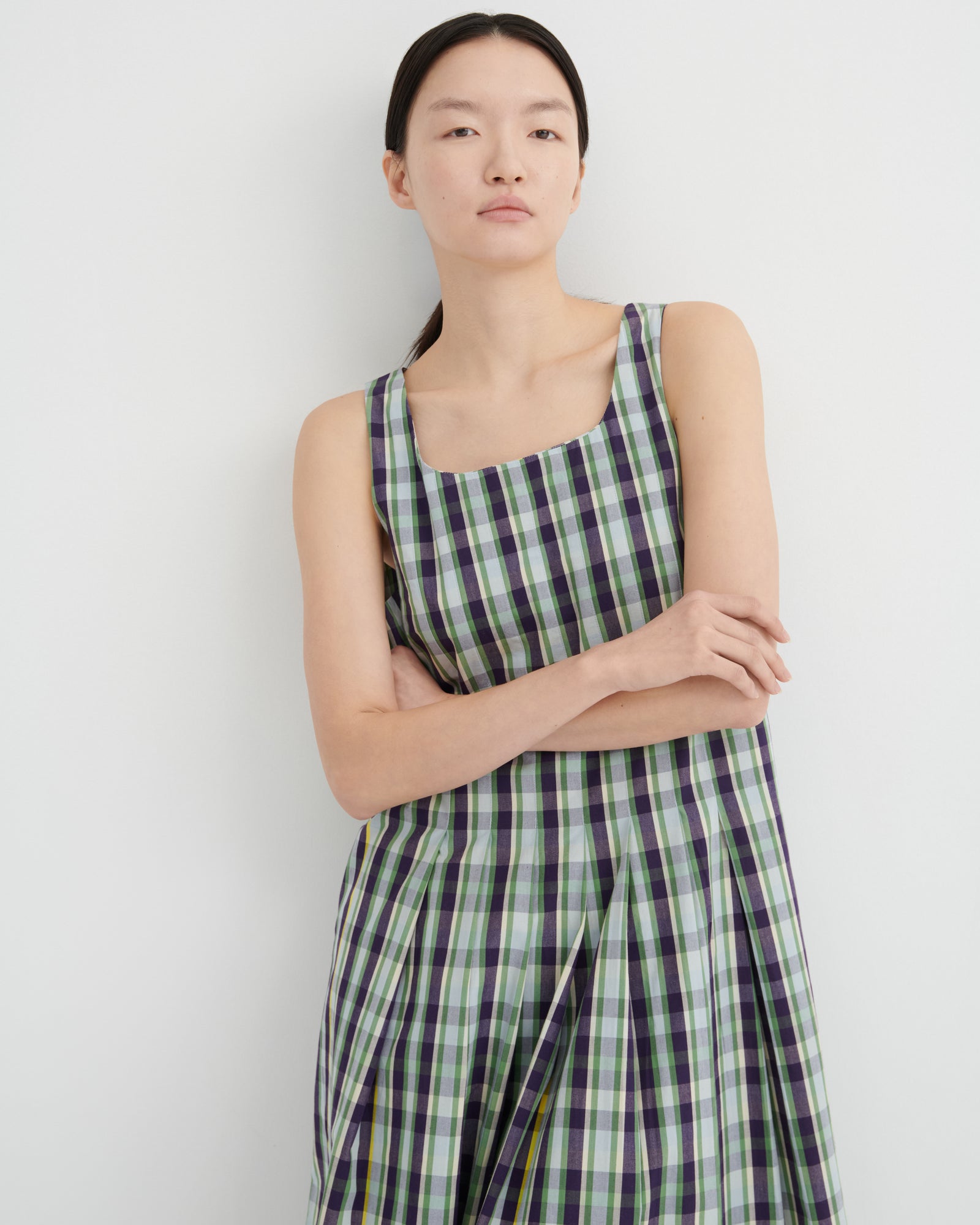 Woman wearing a green and purple checkered dress against a white background