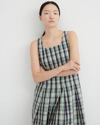 Woman wearing a green and purple checkered dress against a white background