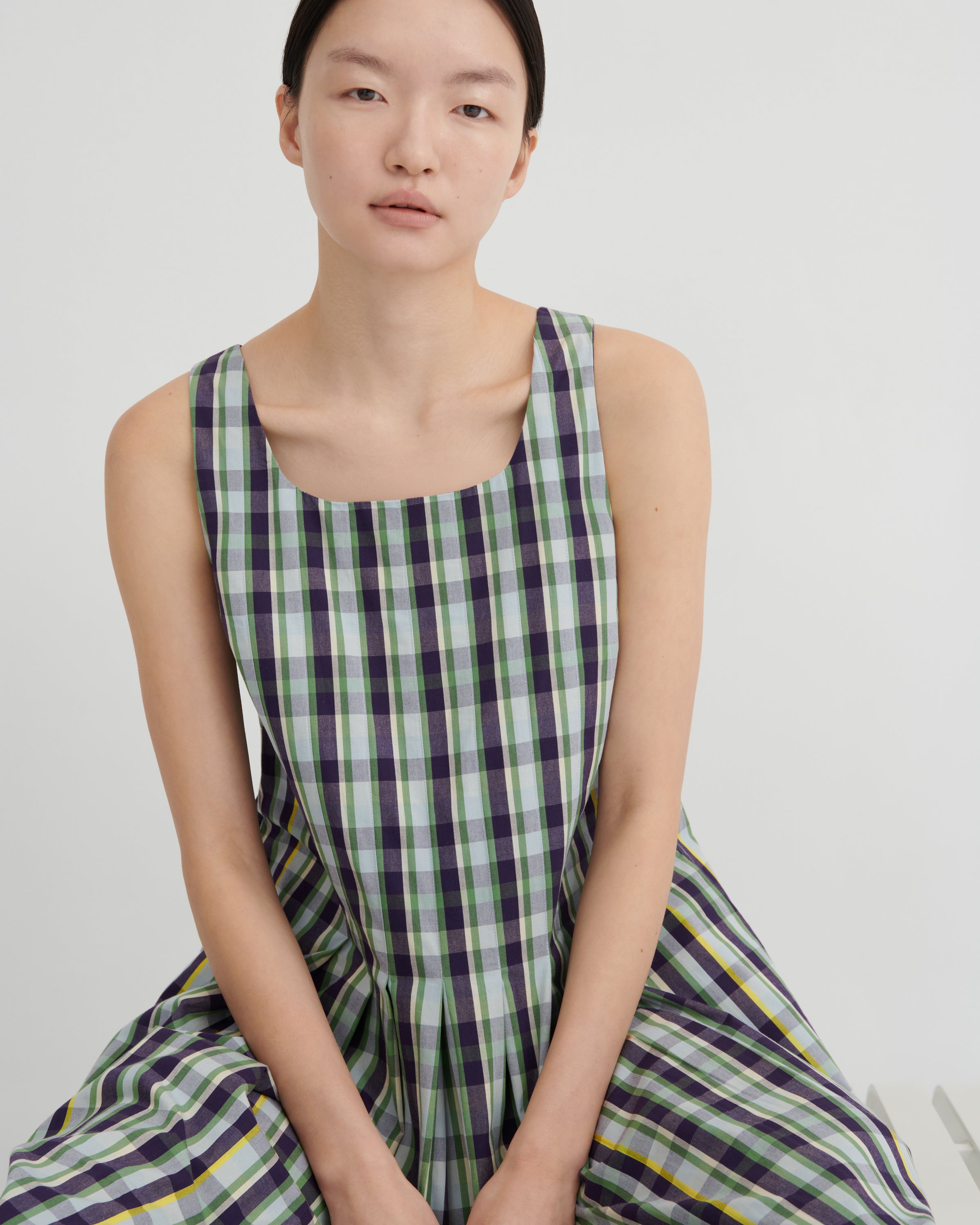 Woman wearing a green and purple checkered dress on a white background
