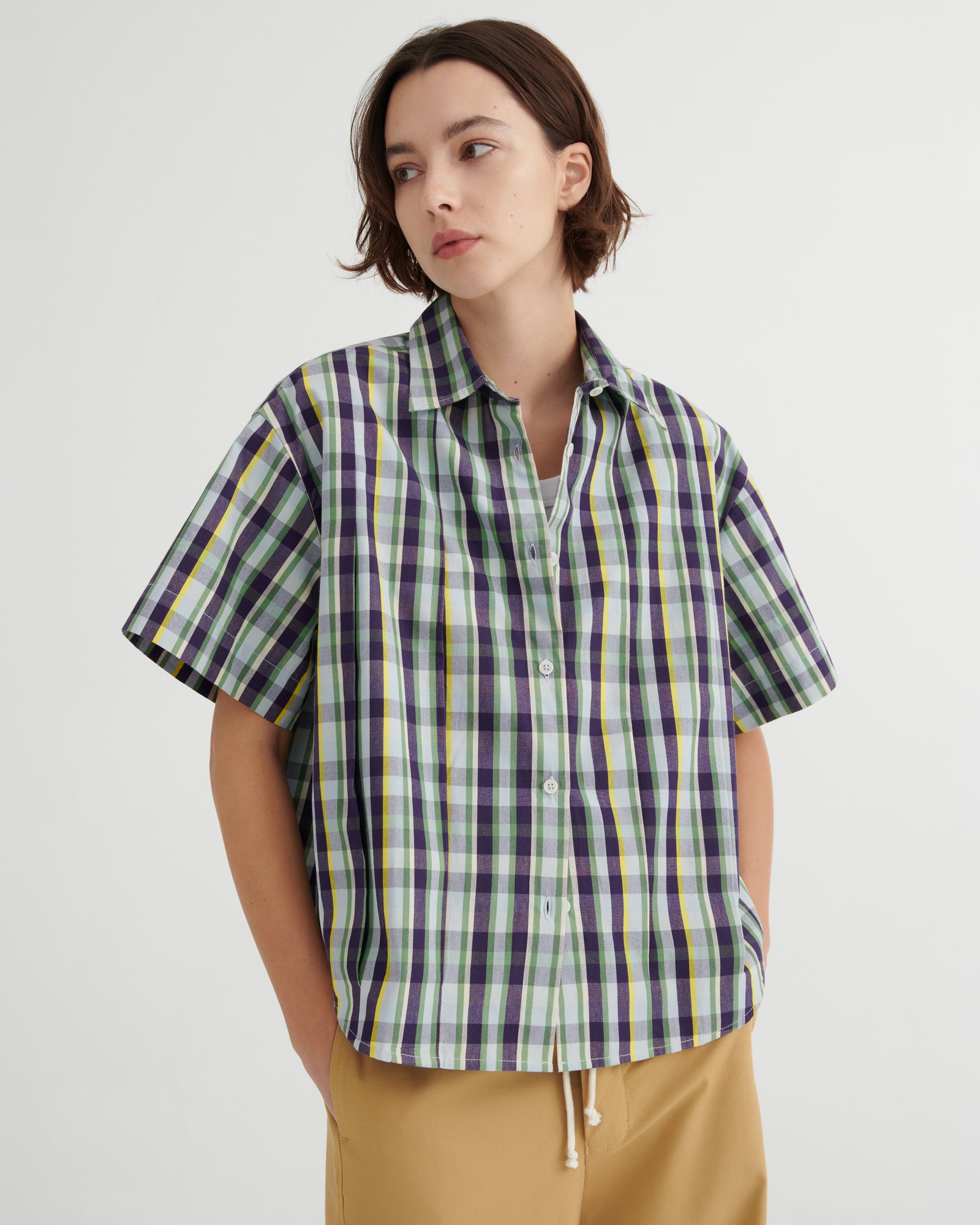 Person wearing a plaid shirt with a plain background