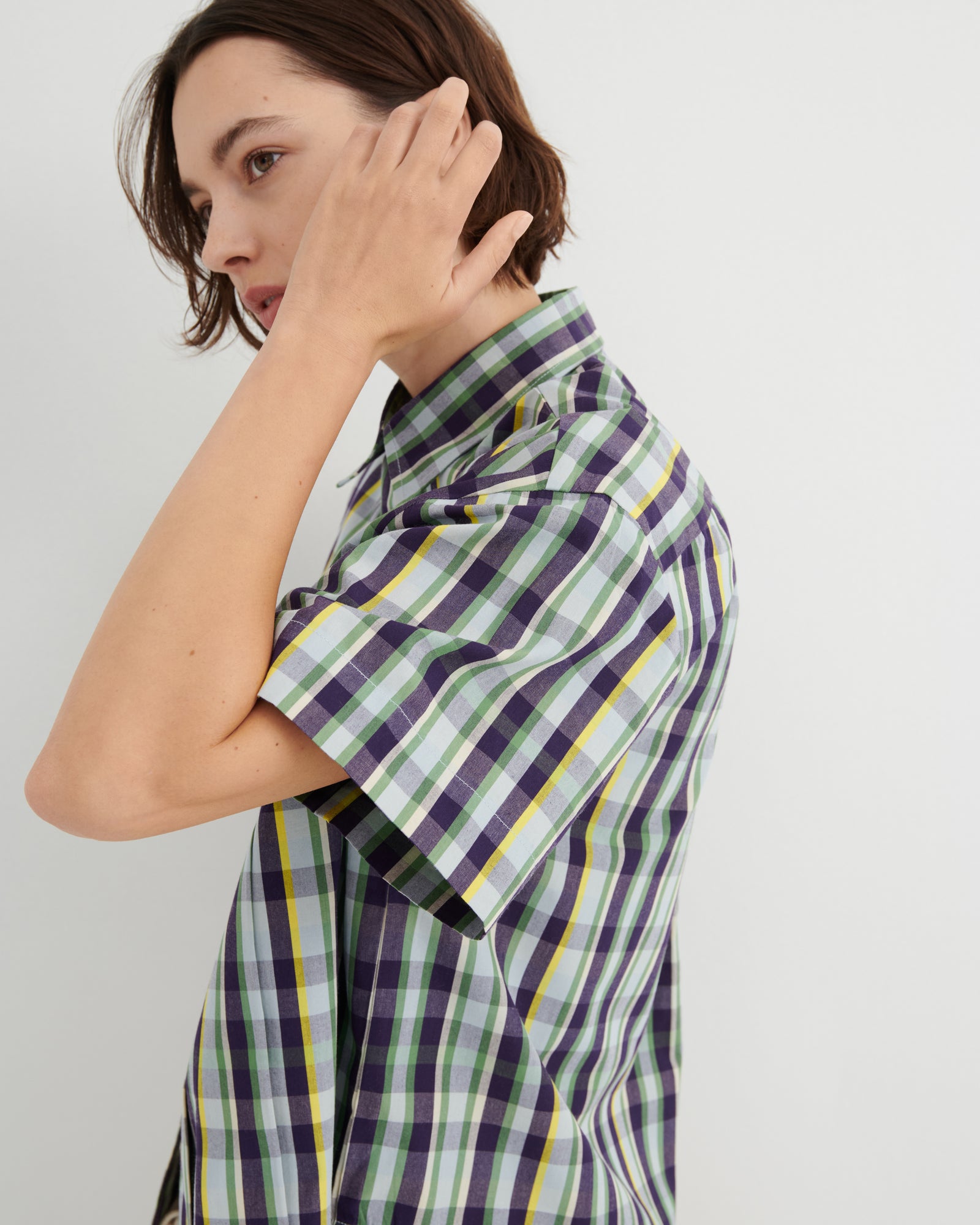 Person wearing a plaid shirt with a neutral background