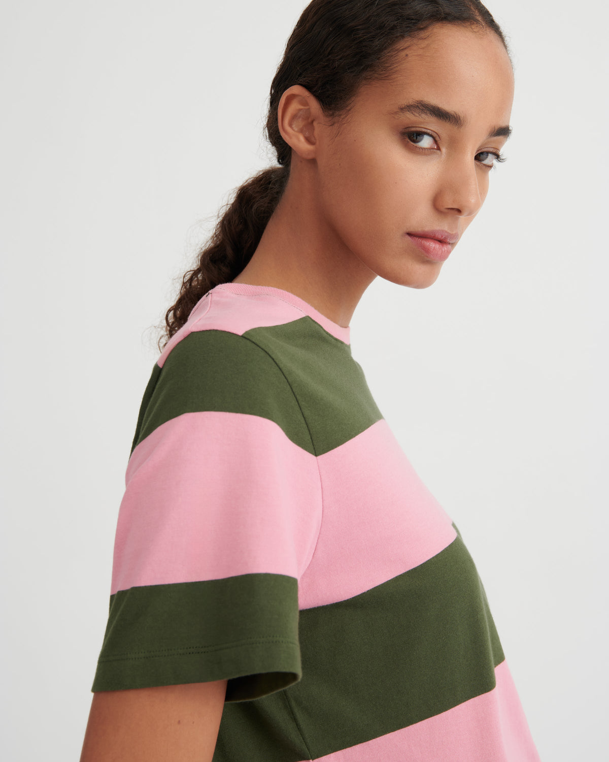 Woman wearing a pink and green striped shirt on a white background