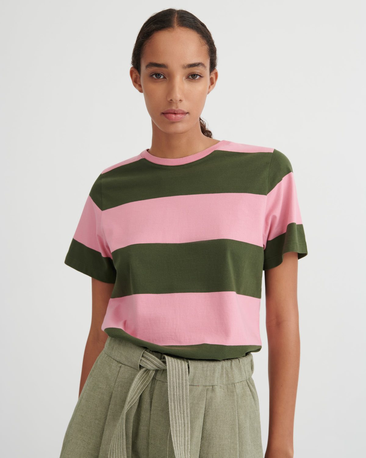 Woman wearing a pink and green striped shirt with a plain background