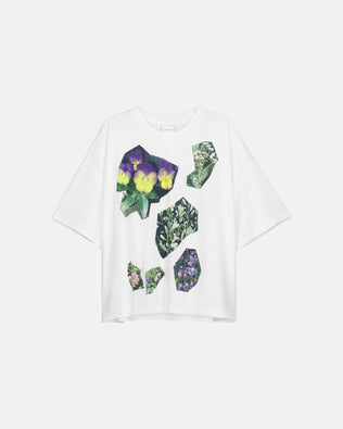 A white short-sleeve t-shirt with a graphic print of purple pansies and green leaves arranged in irregular stone-like shapes on the front, displayed against a light gray background.