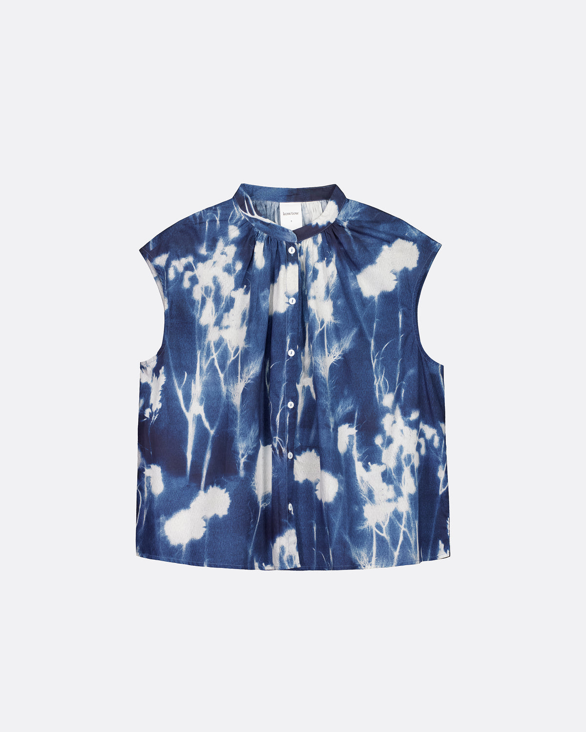 A sleeveless button-front top with a stand collar, featuring a blue and white cyanotype floral pattern, displayed flat against a light gray background.