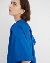 A woman shown in profile wearing a bright royal blue short-sleeve dress.