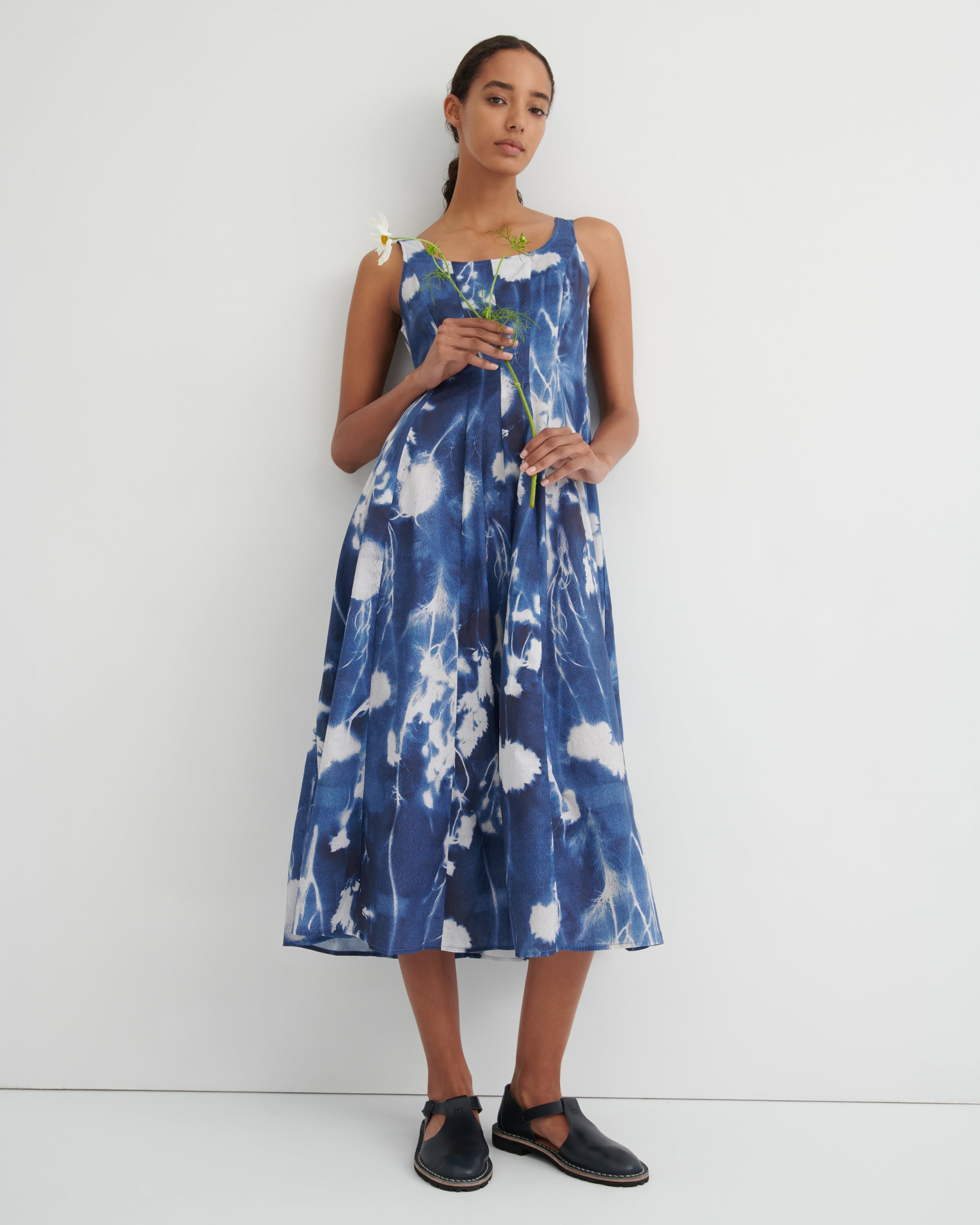 Woman wearing a blue and white floral dress against a white background