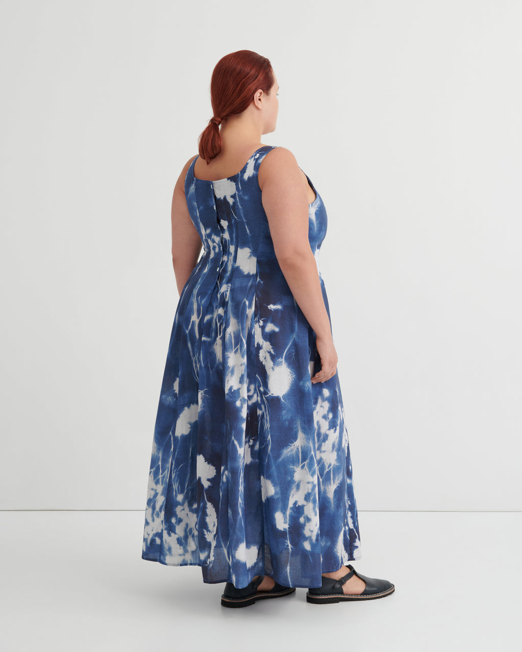 Woman wearing a blue tie-dye dress against a white background