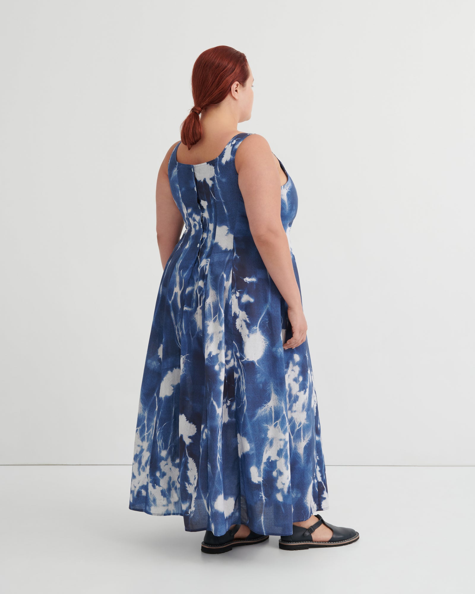 Woman wearing a blue tie-dye dress against a white background