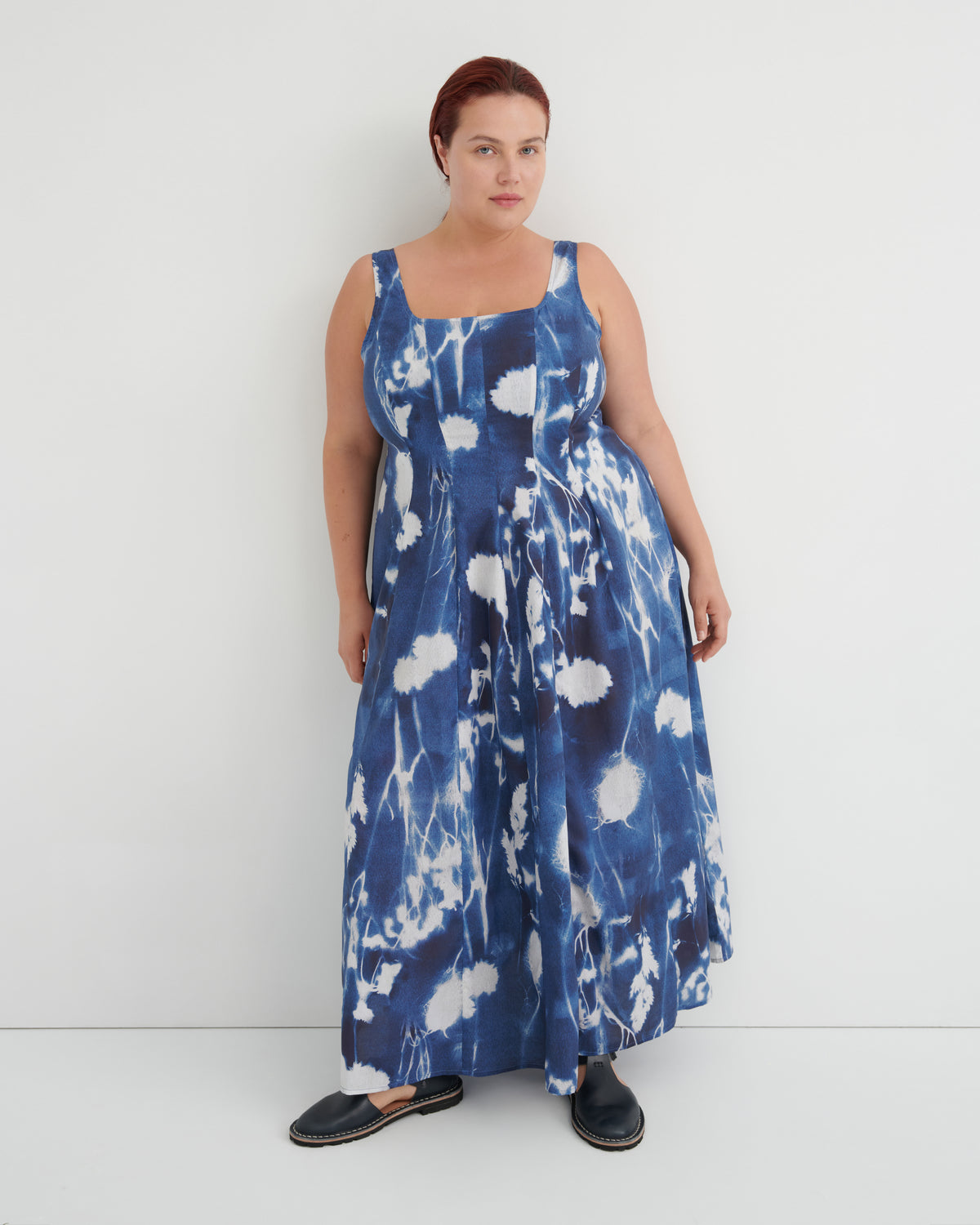 Woman wearing a blue and white floral dress against a white background