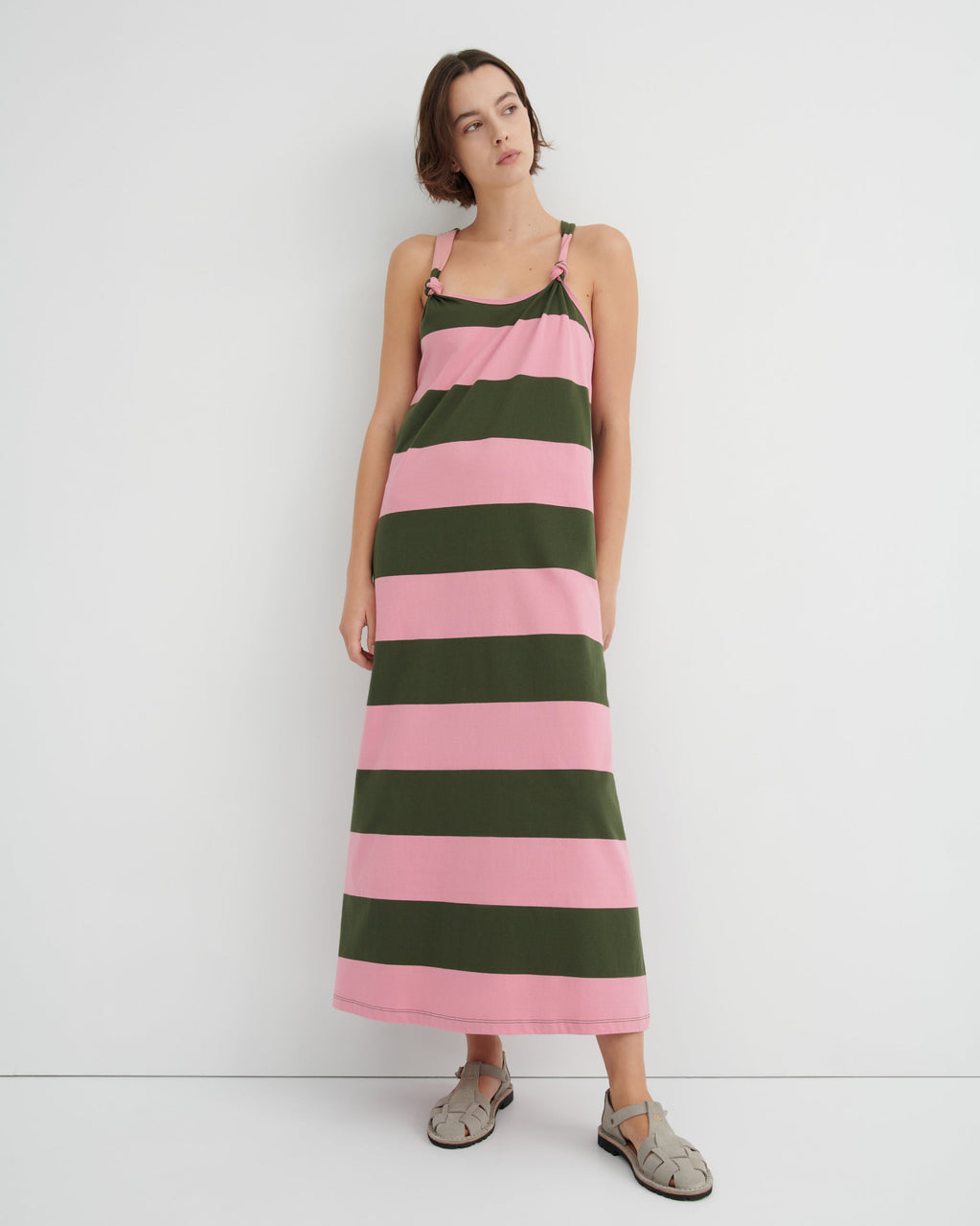 Woman wearing a pink and green striped dress against a white background