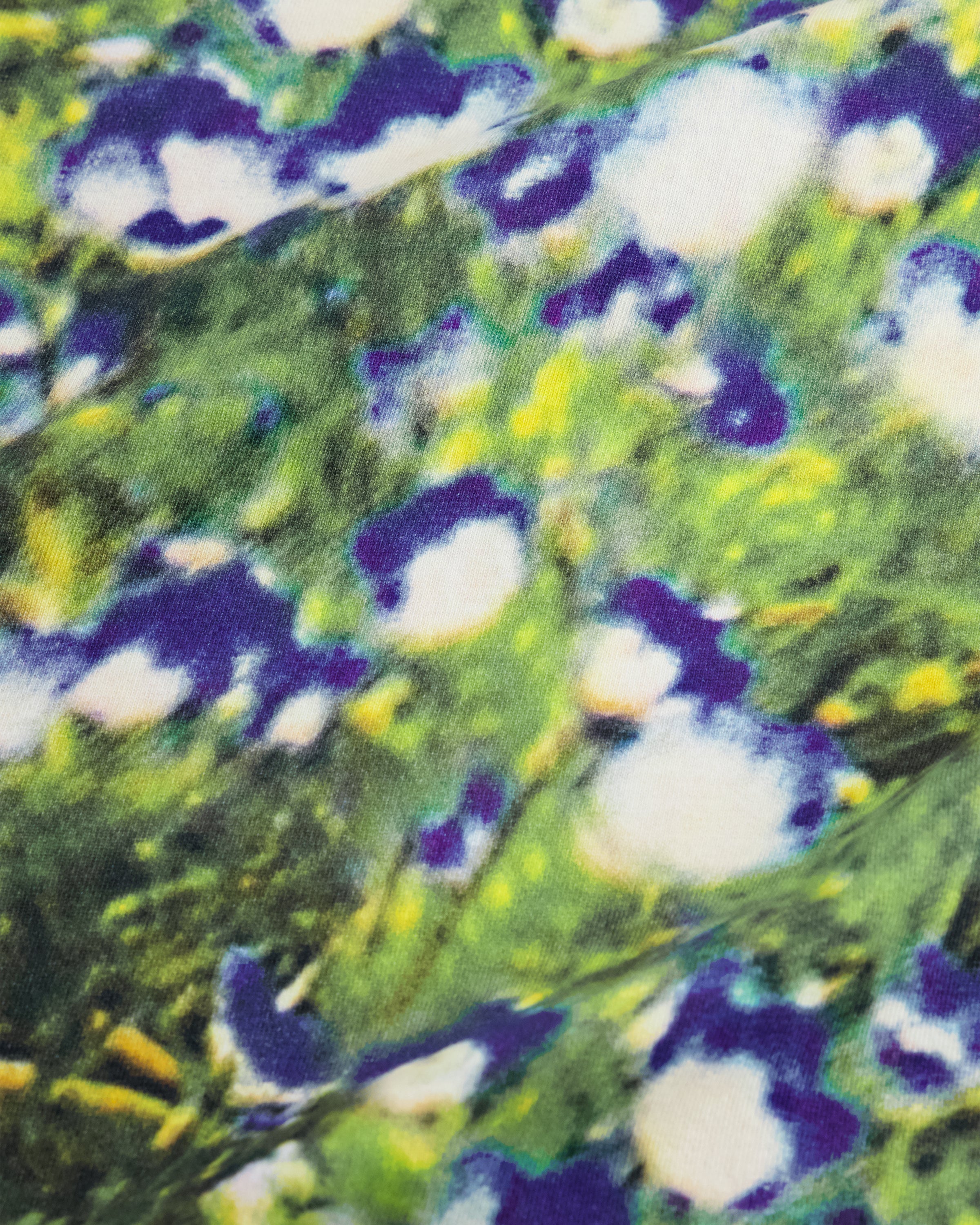 A close-up of a textured fabric or wallpaper pattern featuring abstract organic shapes in green, yellow, purple, and white.