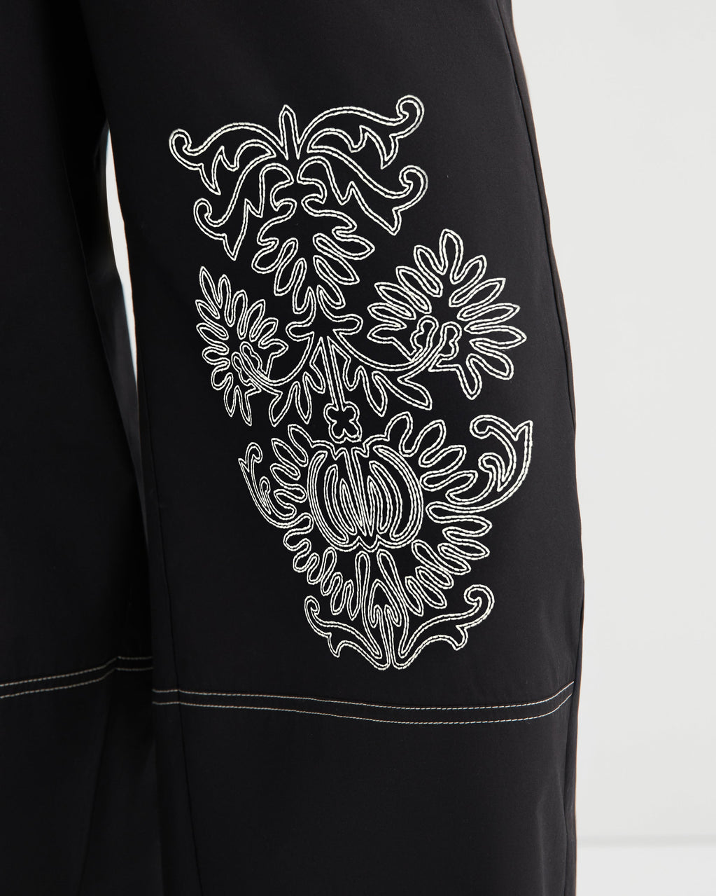Black garment with white embroidered design on a white background