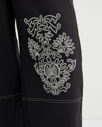 Black garment with white embroidered design on a white background