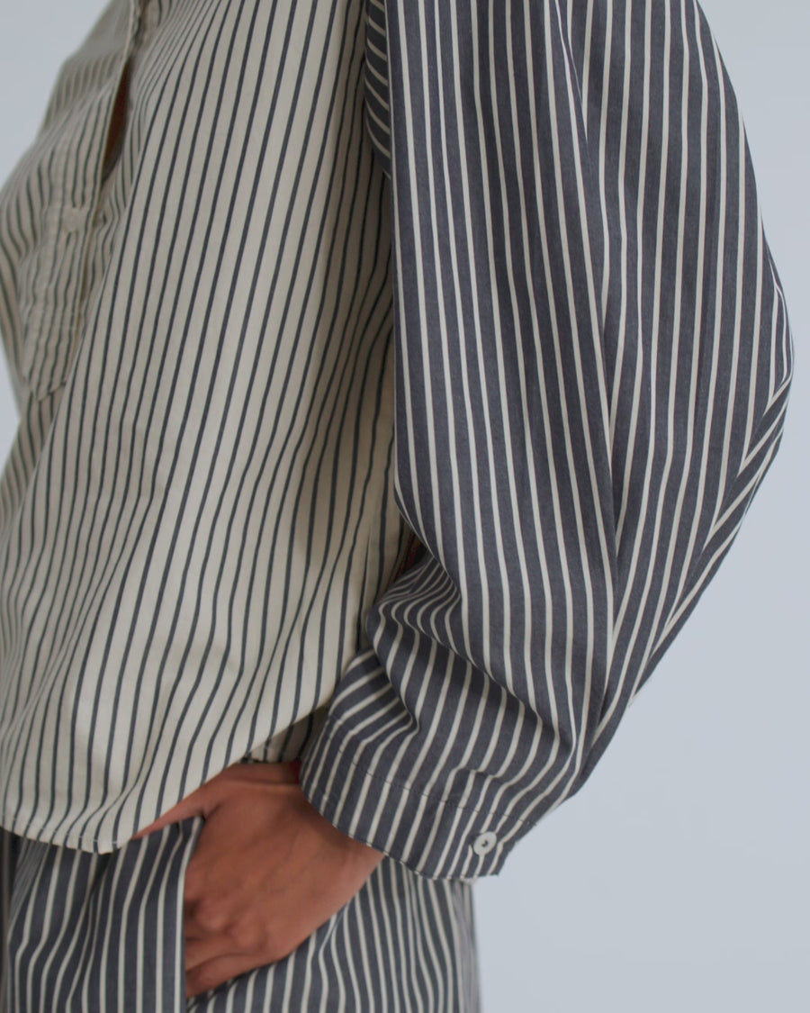 A women wearing matching stripe shirt and shorts against a light grey background.