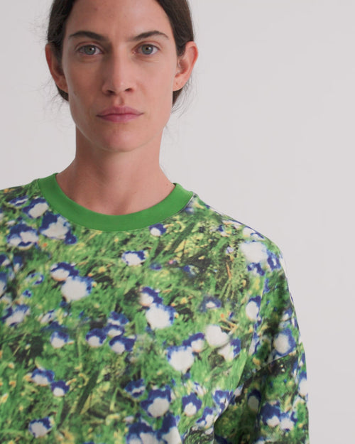 A women wearing an oversized floral tee with dark denim shorts.