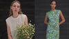 A video of a women wearing a green floral dress against a black weatherboard background.A women sits in front of a black weatherboard background wearing a cream knitted vest and green shorts holding a bunch of daisys.