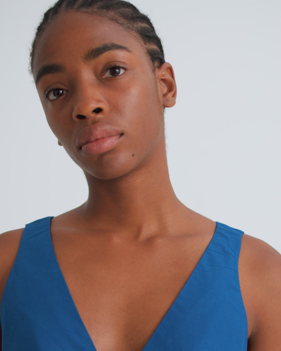 A women wearing a royal blue sleeveless v neck dress.
