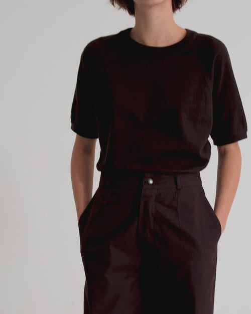 A model wearing a relaxed dark brown cotton knit top and matching brown pants.
