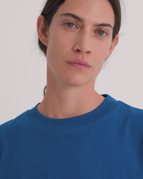 A women wearing royal blue sleeveless tee and wide leg black pants.