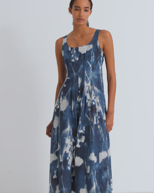 A women wearing a sleeveless dress in a blue cyanotype floral print with a fitted bodice.