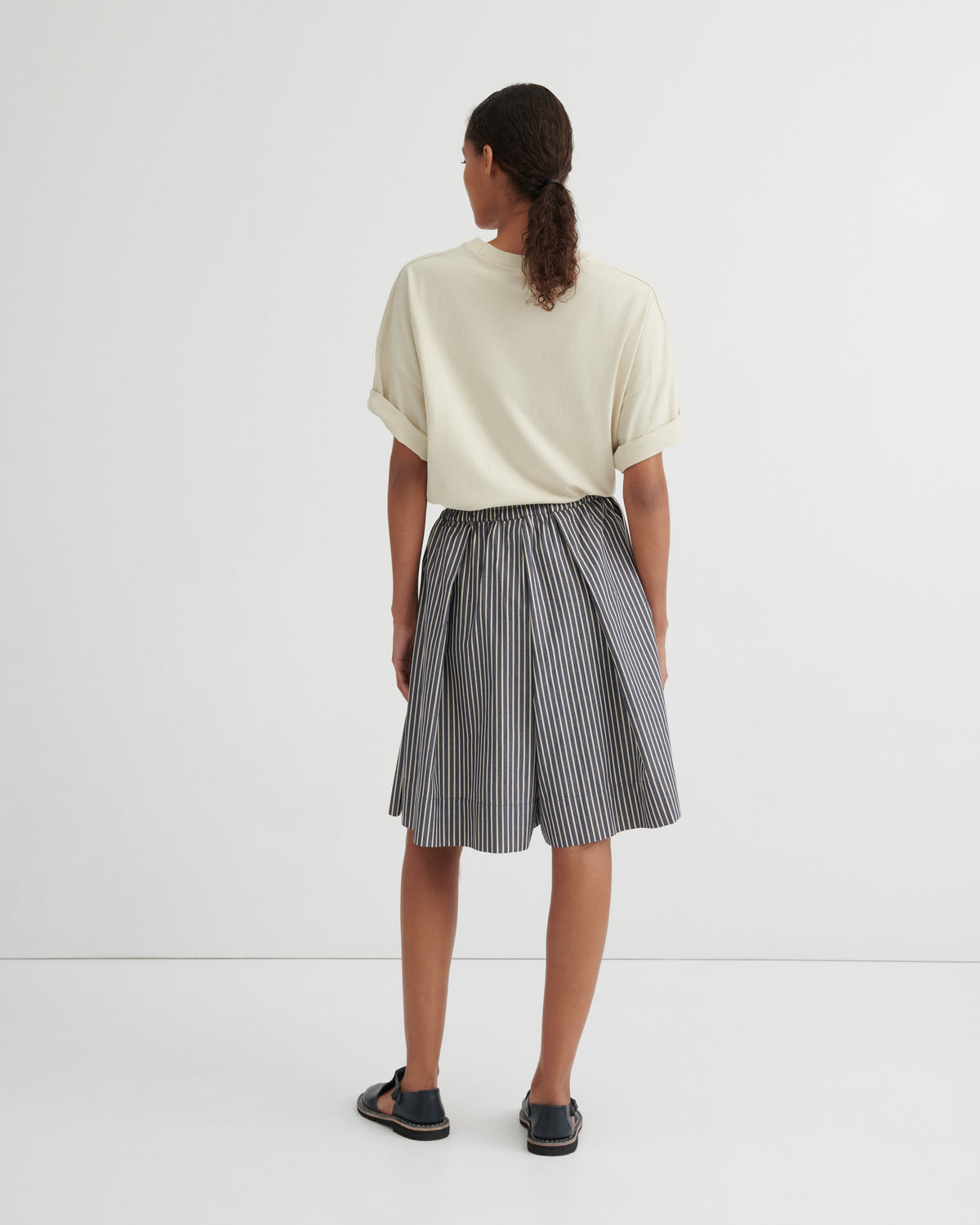 Person wearing a white top and striped skirt on a white background