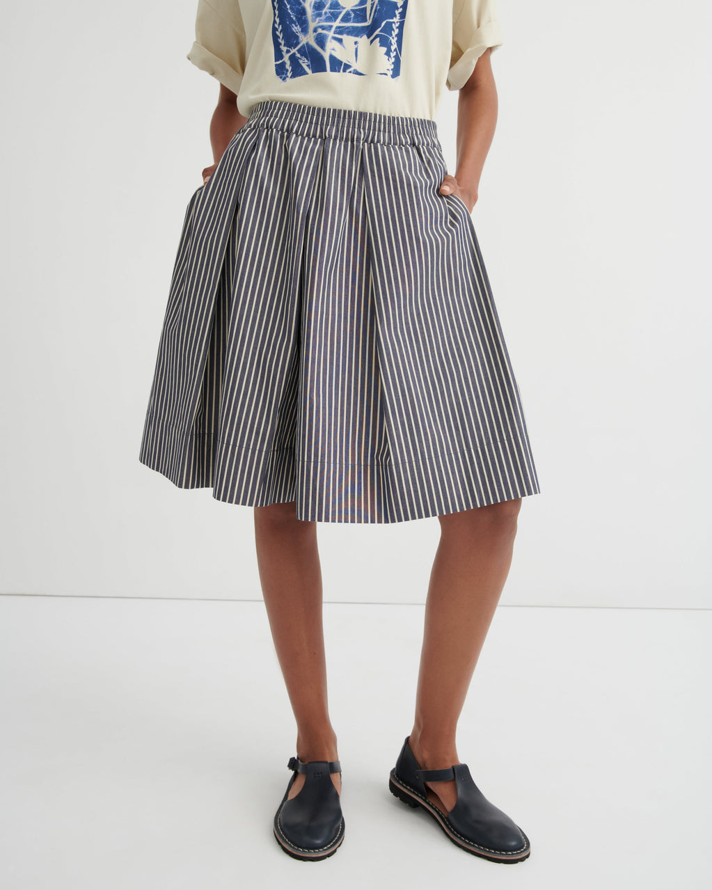 Person wearing a striped skirt and black shoes on a white background