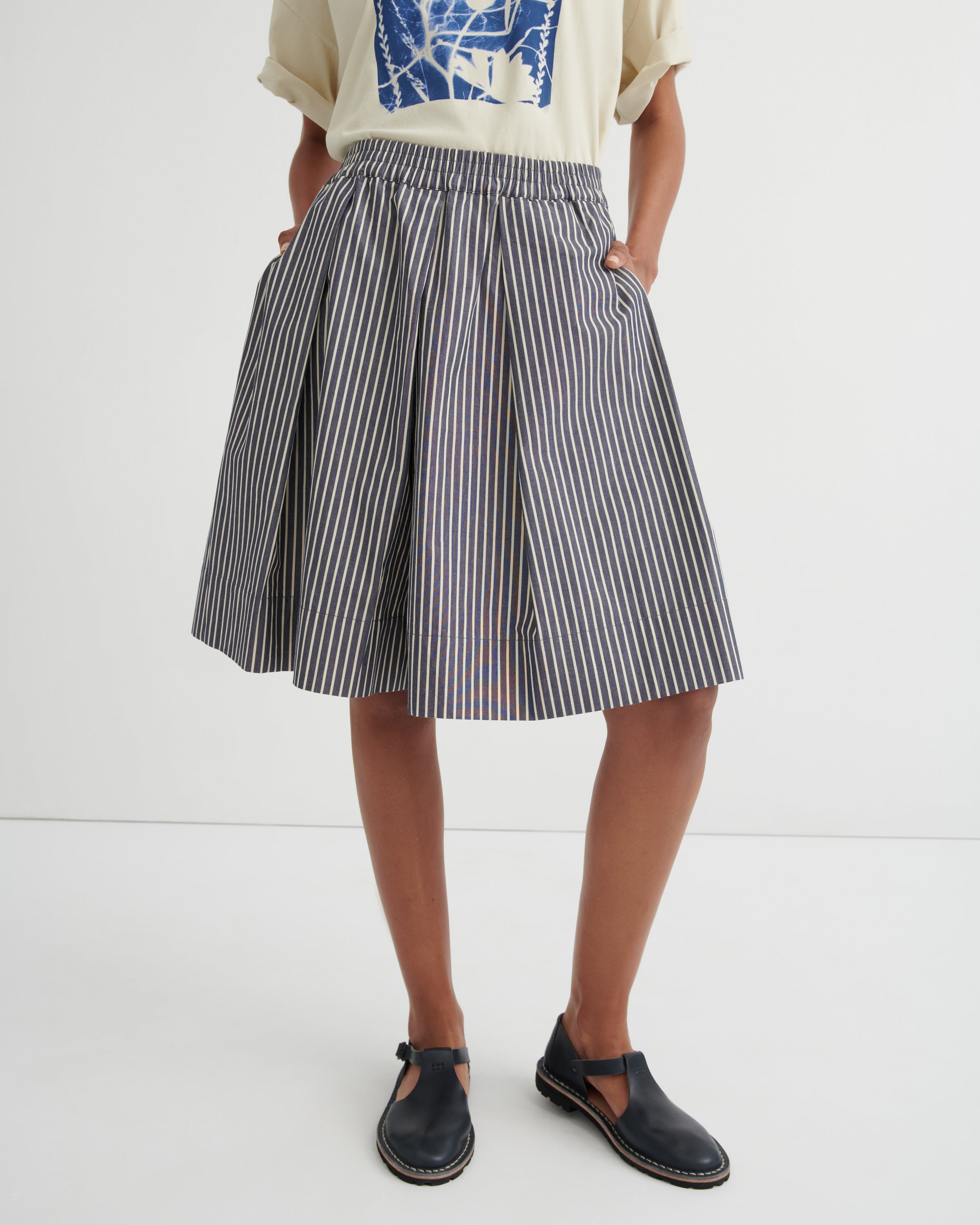 Person wearing a striped skirt and black shoes on a white background