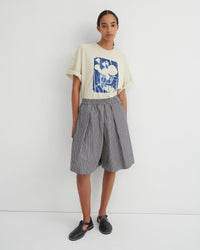 Person wearing a graphic t-shirt and striped skirt on a white background