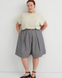 Person wearing a light-colored top and striped skirt against a white background